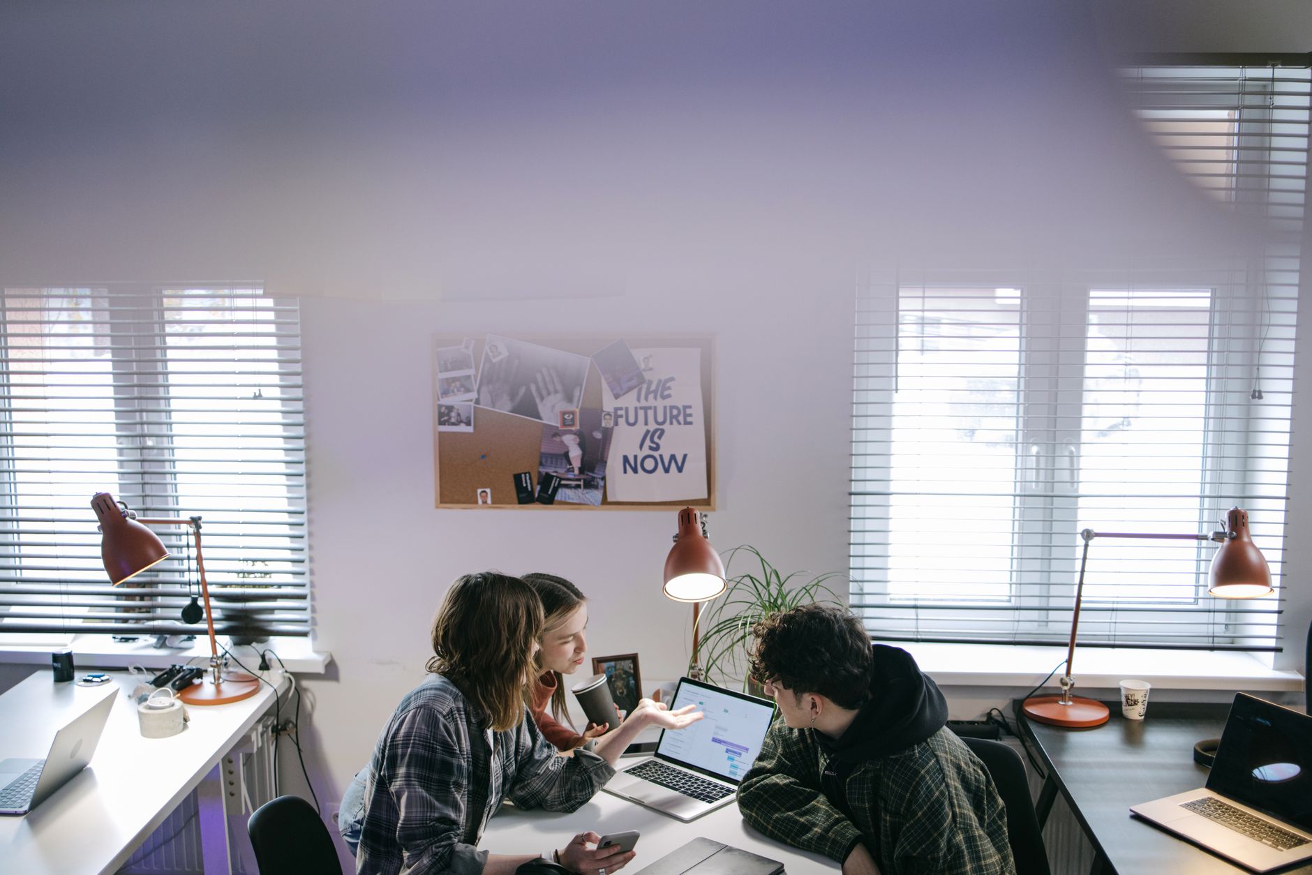 A group of people discussing ideas around laptops in a bright, modern office space — illustrating: Top Remote Management Platforms for Central Florida SMBs: Features, Pricing, and Real-World Performance